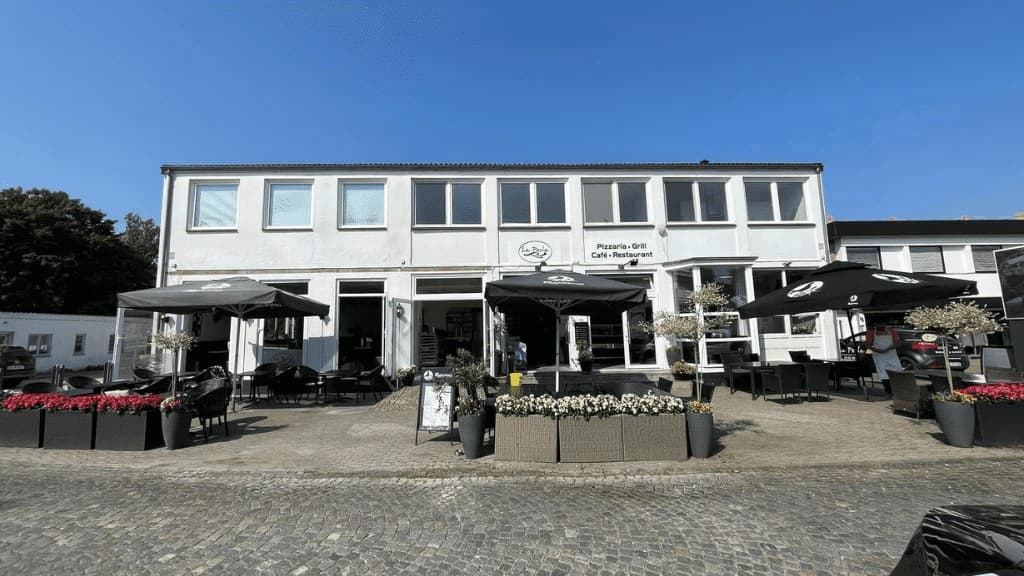 Restaurant La Perlas facade med sorte store, borde og parasoler